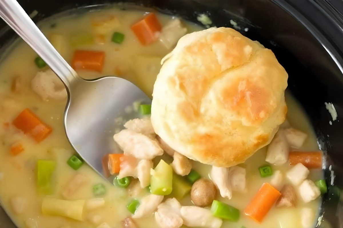 Crock pot chicken pot pie served in a bowl topped with a biscuit, showcasing hearty chicken, vegetables, and creamy filling