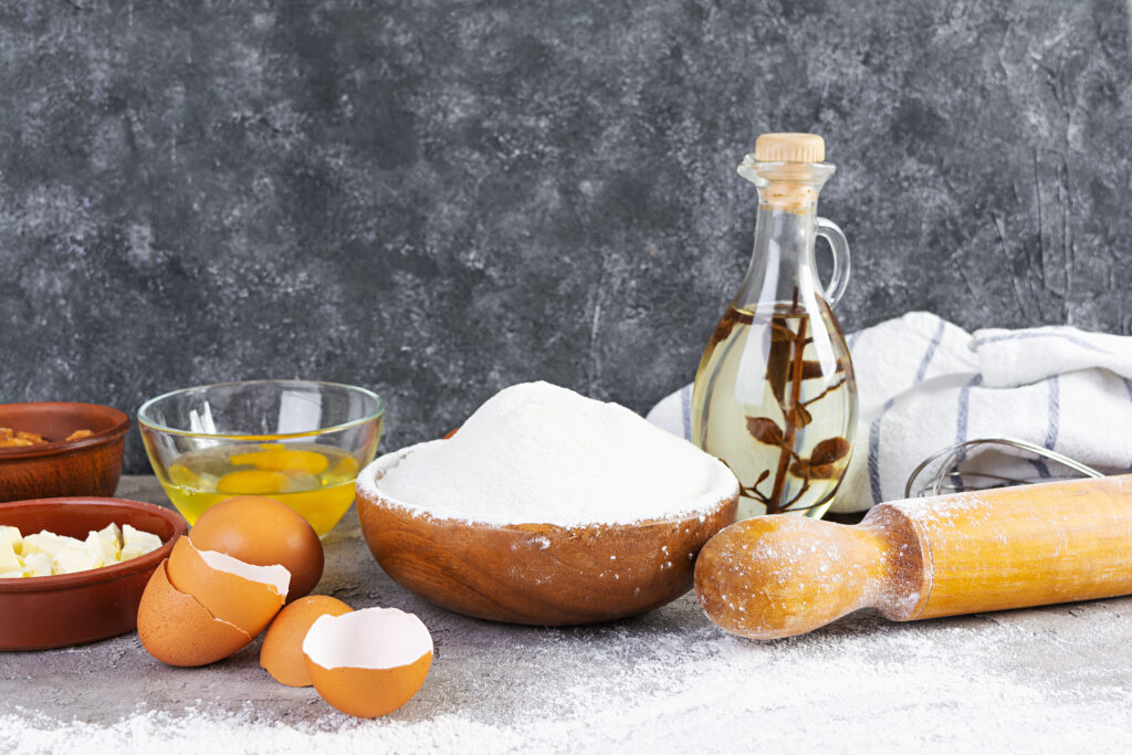 Baking ingredients including flour, eggs, butter, and oil for making dough or bread