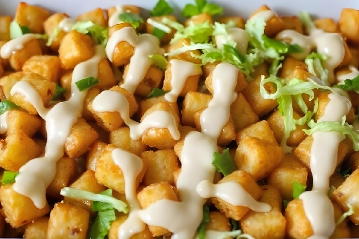 Big Mac Tater Tot Casserole topped with crispy tater tots, shredded lettuce, and special sauce in a white casserole dish.